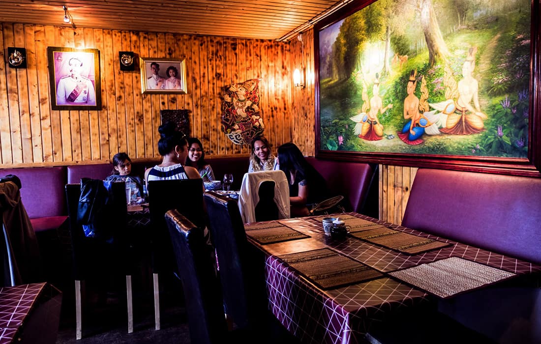 Matsalen på Phuun Thai med trä, thailändska målningar och plommonfärgade dukar